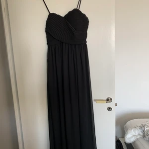Svart långklänning - Superfin svart långklänning, oanvänd då den är för liten. Inbyggd bh, justerbara axelband, dragkedja i sidan och silikonrand vid brösten så den sitter uppe. Storlek 10 eller M