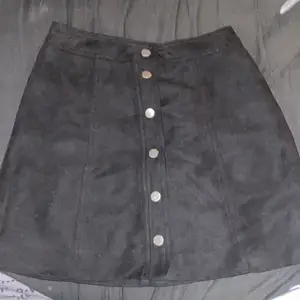 En svart h&m kjol i Sämskskinn med metall knappar, den sitter jätte fint på. Ny och aldrig använd då det inte är min stil längre men annars jätte gullig😊🖤!!