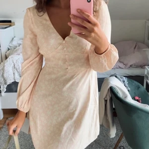 Blommig Sommarklänning från Nelly - Söt klänning från Nelly med knappar framtill och långa ärmar. Inköpt i september förra året, säljer pga att den tyvärr blivit för stor för mig. Använd en gång.