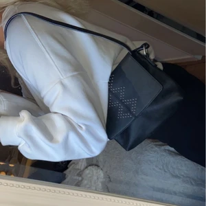 Svart väska med silverdetaljer  - Svart väska med coola detaljer, väskbandet går att justera så man både kan ha väskan som på bilden eller som en axelbandsväska 
