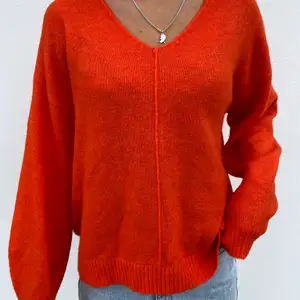 En orange stickad tröja med en v ringning 