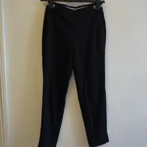 Svarta byxor från H&M med svart/vit rand baktill.