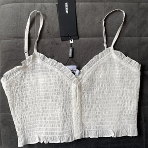 Weekday topp, oanvänd  - Jättefin vit top ifrån weekday, storlek xs. Helt oanvänd med prislapp kvar. Säljs då den inte kommer till användning! Köpt för 300kr, men säljs för 100+frakt. Vid fler intresserade blir det budgivning. Hör av er vid frågor och kontakta för fler bilder💖