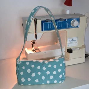 Egensydd baguette bag - Egensydd baguette bag i babybluemönstrat tyg. Grått innertyg. Dragkedjan är ca 20cm lång, hoppas det ger en inblick i väskans storlek.