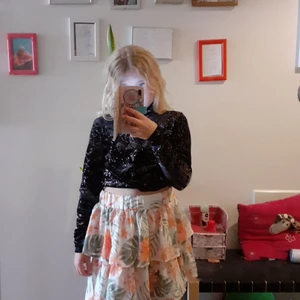 Svart tröja med glitter  - Långärmad tröja med knut där fram och en liten öppning i ryggen och har glitter som bildar mönster. Jag vill sälja denna eftersom att a den är för stor för mig, men den är i super bra skick och har endast använts en gång. 