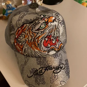 Ed Hardy keps  - En ed Hardy keps som är silver glittrig med en tiger på framsida och så diamant pärlor typ, den är (äkta)