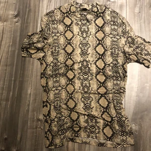 Tight-fitting tröja i ormmönster - Ny tröja som jag använt en gång, stretchigt och skönt material, storlek M men passar i princip alla då materialet är väldigt töjbart.Tröjan har en hög krage med armar som är medel långa.