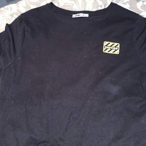 En svart tröja med tryck på bak och fram sidan, storlek L, Använd men i gott skick 
