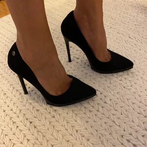 Svarta pumps med spetsig tå - Aldrig använt då de är något för stora för mig som har 36,5 i strl. Dessa snygga pumps med fin detalj på plattformen är i strl 3 UK. Jag tror att de hade passat bra för en som har storlek 37. Materialet i ovandelen är i konstmocka. Klackhöjden är ca 10-11cm. 