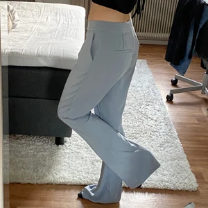 Kostymbyxor - Gråblå kostymbyxor från Na-kd, väldigt bra skick. Sitter lågmidjat på mig som vanligtvis har 34/36 på byxor. Är 166 cm lång.
