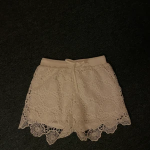 Korta byxor - Korta vita tygshorts. Broderat mönster på utsidan sitter inte fast på det andra tyget. Skönt material. Stretchiga med snöre att knyta. 