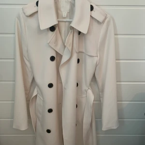Vit Trenchcoat från Hm, aldrig använd - Säljer min vita trenchcoat från hm, stl. 38 men passar bra som 36 också. Aldrig använd. 