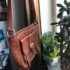 Brun väska - Mindre brun väska från HM i skinnimitation. Köpt second hand dock aldrig kommit till användning. Fräsch inuti och i fint skick. Möts upp eller fraktar💚