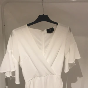 Vit klänning  - Supersöt Vit klänning i omlottmodell. Dragkedja i ryggen och med fina volanger!! Storlek s och sparsamt använd💫💫 Perfekt till student eller skolavslutning! 