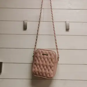 Snygg rosa väska med guldiga detaljer från newyorker, köpt för 250 kr. Aldrig använd. Tänkte sälja den för 100 kr. Vi kan disskutera priset.  Frakt kostar 66 kr