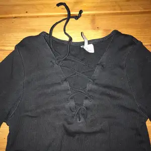 En svart T-shirt med snören framför urringningen