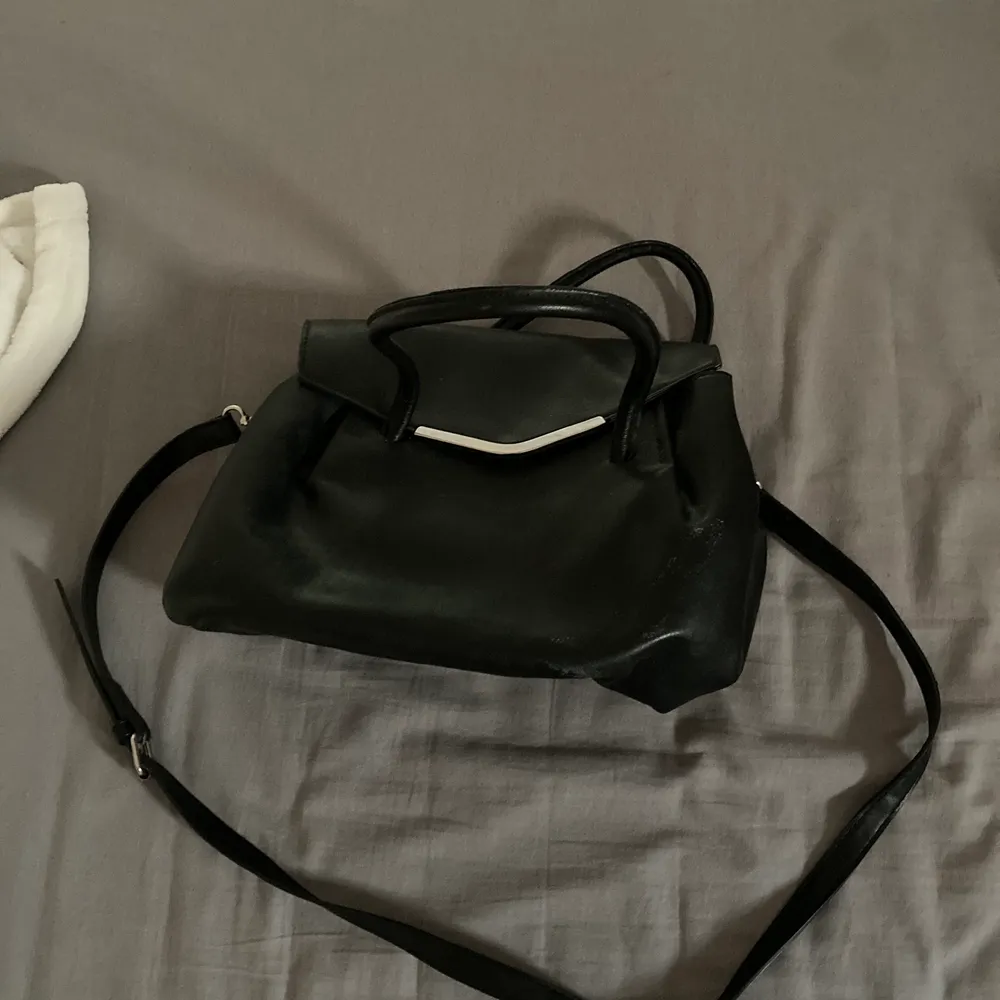 En svart handväska. Kommer inte ihåg var den är köpt då den är rätt gammal men aldrig kommit till användning.. Väskor.
