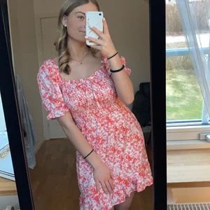 Rosablommig sommarklänning - Rosa kortklänning, perfekt på somaren!💗 Söta blomdetaljer, rosett där fram, bra passform då de d resår. Aldrig använd. 