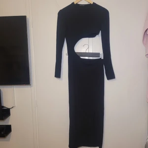 Svart lång klänning - Som det kanske syns dåligt på bild är att den är helt öppen mellan top och kjol då den bara sitter ihop på ena sidan. Har en slit.