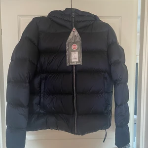 Helt ny colmar jacka - Endast testad 1 gång. Storlek 42 men skulle säga att dom är en aning små i storleken, passar mig jätte fint som är en 38/40a. Marin blå. Köptes för nån månad sen för 4800kr, säljes då jag inte använder den som jag trodde. Modell: 7QD 2216 PLACE Snitt: dragresår i kanten, rak Mått vid storlek 36: Modell-längd 57 cm, Armlängd 64 cm Krage: Ståkrage med avtagbar huva Knäppning: genomgående dragkedja Ärm: elastiska muddar Ytterfickor: blixtlåsficka(or) Innerfickor: innerfickor vänster och höger 