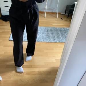 Svarta vida kostym byxor med band  - Jag säljer dessa svarta vida kostymbyxor från Bikbok i storlek xs. Dessa är i väldigt bra skick då dem är oanvändna. Jag är runt 160 cm och passar jättebra i längden. Dem sitter inte tajt utan är ganska lösa. Dem sitter fint i midjan och inte så tajt runt låren och ner. 