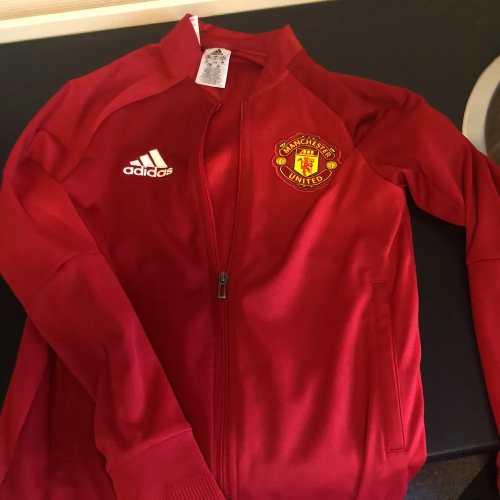 Sällan använd röd sweatshirt med zip från Adidas samt tryck med fotbollslaget Manchester United, Storlek 164. Hoodies.