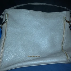 Michael Kors väska  - Äkta läder, beige färg (lite mörkare än på fotot) rymmer en IPad och har innerfack. Inget slitage på själva lädret, dragkedjan är dock sönder. Säljes då jag inte använder den för jag föredrar bruna/svarta väskor. Köparen står för frakt 