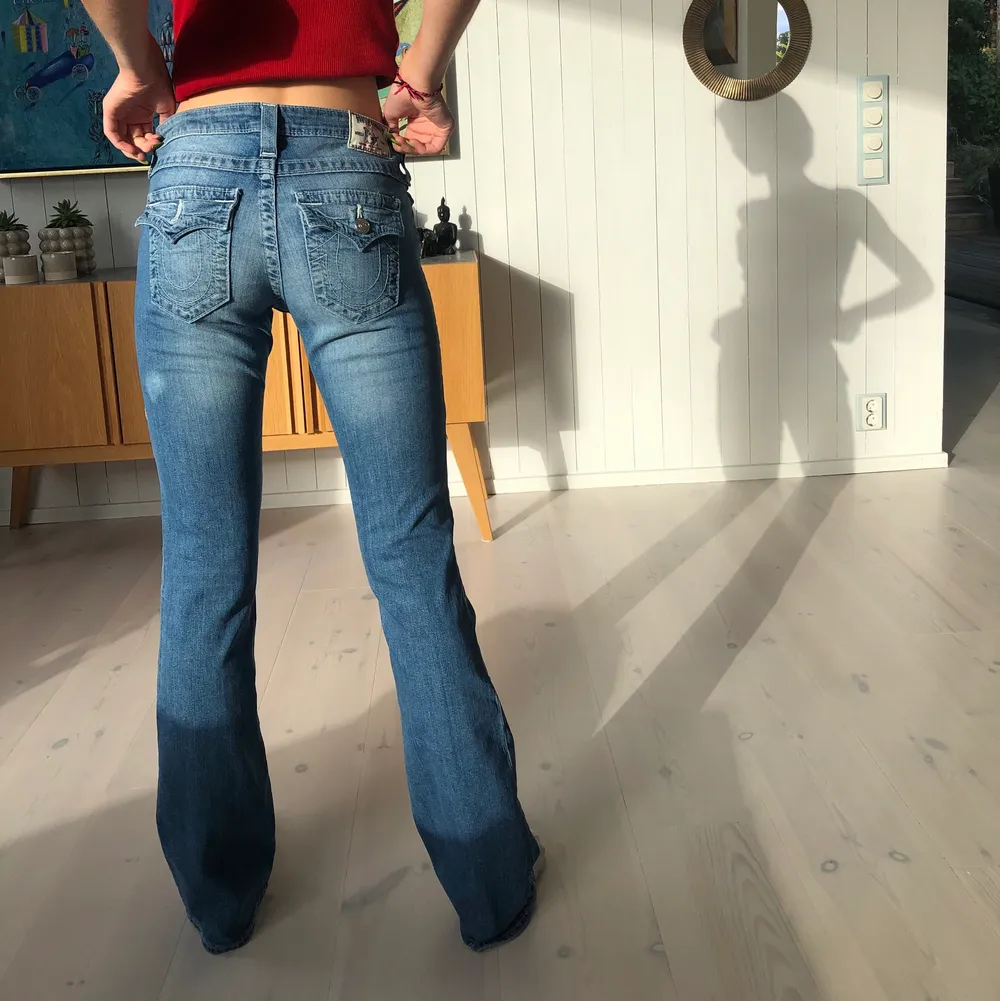 Asfina och superpopulära True Religion jeans! Dessa är jätteeftertraktade och de perfekta y2k jeansen. Lowrise och bootcut🤩 En knapp saknas tyvärr på ena fickan (bild 3) men annars perfekt skick! Modellen är 172cm och byxorna räcker ner till golvet på henne. Kan mötas upp i Sthlm eller frakta (då står köparen för frakten). Hör av dig vid frågor!🥰💞. Jeans & Byxor.