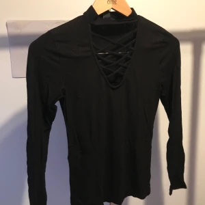 Svart tröja - Svart långärmad tröja med kors detalj vid brösten. Använd ett fåtal gånger.