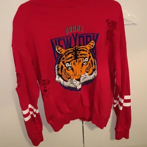 Tröja  - Röd tröja med rips och ett tiger motiv, säljer då den inte e min stil längre. 75kr