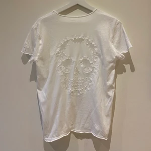Vit Zadig & Voltaire t-shirt - Vit Zadig & Voltaire t-shirt med en döskalle i spets i ryggen. Använd ungefär 2 gånger så den är i väldigt bra skick. Säljer då det inte riktigt är min stil längre. Pris: 400kr (originalpris: runt 1000kr)