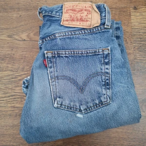 Vintage Levi's  raka jeans 501 "Mom jeans" - Säljer dessa fina levis jeansen. De är i fint begagnat skick men det finns slitningar här och där som ni kan se på bilderna. Jag har mätt jeansen på golvet och fått fram måtten:  Beninnerlängd: 78 cm, midjemått:  35 cm. Bud från 250 kr. Auktionen avslutas Fredag den 26/2 kl 20:00. Jag vill gärna att ni budar i kommentarerna. 👖💟  Jag kan tyvärr inte ha jeansen så jag kan inte visa hur de sitter på :/