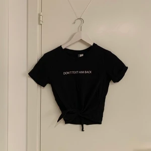 Croppad svart t-shirt med tryck - Svart t-shirt som går att knyta fram med tryck i strl XS från H&M. Fint skick. 