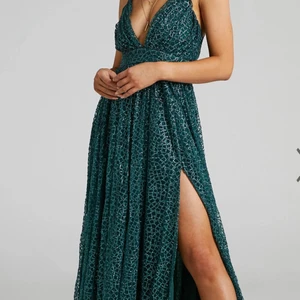 Balklänning med glitter - Smaragdgrön glittrig klänning med slits pch öppen rygg. Aldrig använd, storlek 44 pch passar någon som bär L-XL. Köparen står för frakt<3 Kan mötas upp i Eskilstuna/Örebro💚