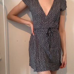 Omlottklänning - Supersöt klänning från Brandy Melville i fint skick, köpt i Portugal. Den är i storlek ”one size” men skulle säga att den passar xs-s bäst. Blå med små vita blommor och omlottknytning.