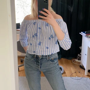 Randig blus  - Blå, randig off shoulder blus med broderade blommor (endast på framsidan) från hollister. Använd max tre gånger så den är i väldigt fint skick. Storlek XS men passar även S. Hör av dig vid intresse! 💙 (köpare står för frakt)