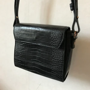 Svart väska, krokodilmönster - Snygg svart väska i litet liknande modell som hvisk. Krokodilskinn, men förstås fejk. Litet fack inuti. Litet använd insida men toppen på utsidan! Underbar, men har för många.  Kan mötas i Stockholm eller skicka mot fraktkostnad! ✨🌸✨