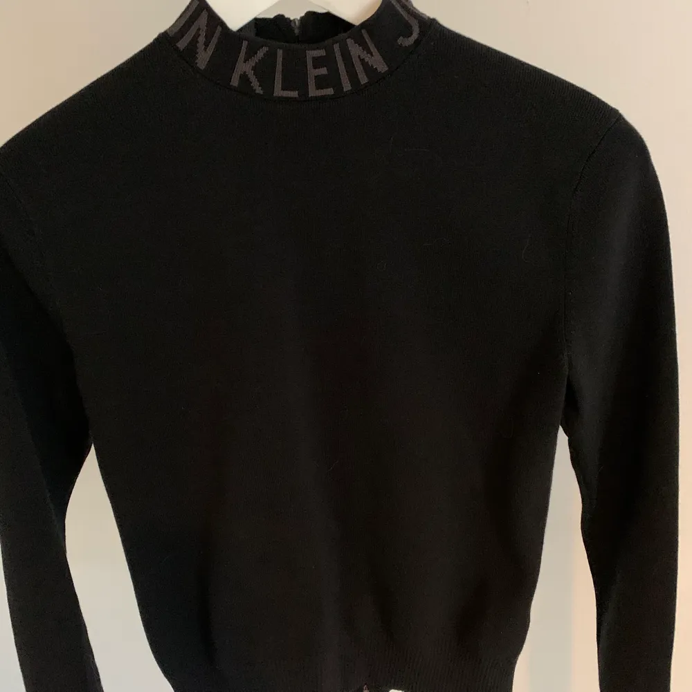 Svart polotröja från Calvin Klein med dragkedja i ryggen och logga på kragen. Skönt och stretchigt material. Använd bara  ett fåtal gånger så den är i bra skick (det är spegeln som är fläckig på bilden och inte tröjan). Strl XS💜. Tröjor & Koftor.