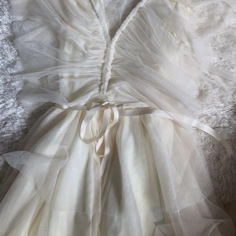 Aurora Dress Ivory från Ida Sjöstedt, vit miniklänning i tyll med vit snöre vid midjan som är justerbart. Klänningen är så gott som ny och helt oanvänd, prislappen är kvar.. Klänningar.