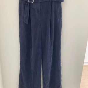 Mörkblå kostymbyxor i manchester stil strl 38 - Mörkblå kostymbyxor i Manchester stil strl 38. Vida ben, hög midja. Använda fåtal ggr och är i gott skick. Säljer även matchande kavaj/blazer.