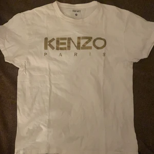Kenzo t-shirt strl S, guldigt motiv - Knappt använd, motivet är i guld och tröjan vit, köpt för ca 700kr, säljer för 150kr.