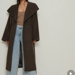 LÅNG KAPPA - Den populära SLUTSÅLDA svart lång kappa från NA-KD, (nypris 1400kr). Använd fåtal gånger, nyskick. Samma storlek som på modellen! (Första bilden är en brun kappa för detaljer syns mer)