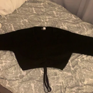 Svart stickad långärmad - Urringad, från hm i storlek xs, kan även knytas om man nu vill de
