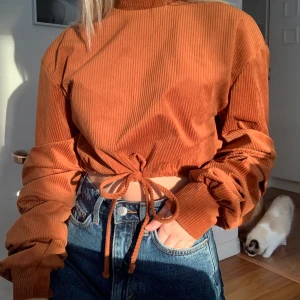 Superfin tröja med öppen rygg - Tröja med öppen rygg, ”veckade” armar, hög hals och knyt i midjan! Den är dessutom i ett sammets liknade material på utsidan (SÅÅÅ mjuk) i en orange/brun färg! 💕 Använd 2-3 gånger så i väldigt bra skick, som ny.