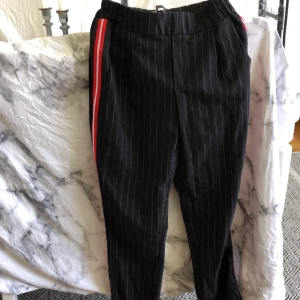 Randiga kostymbyxor - Randiga kostymbyxor med en röd/vit rand på sidan. Säljer då dom tyvärr är för små :( Pris kan diskuteras 