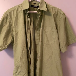 Grön skjorta - Grön skjorta i storlek M från Melka. Superskön och passar bra under en kofta, väst eller som den är. Toppskick och säljer eftersom jag har en likadan. Bara att höra av sig vid frågor och funderingar!🥰🥰