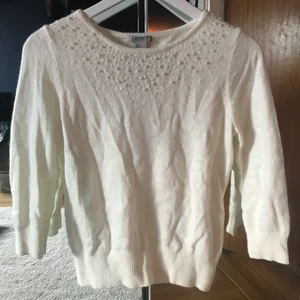 Stickad vit tröja med pärldetaljer - Säljer en stickad vid tröja med pärlor vid halsen. Den är från H&M i storlek s. Armarna är 2/3 med ”muddar”💕