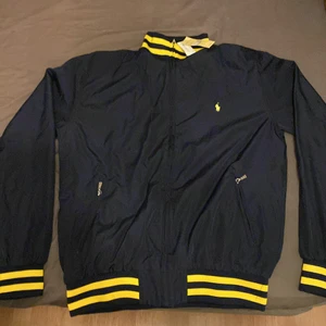 Polo Ralph Lauren - En mörkblå jacka med gula detaljer. Storlek m, Finns inget kvitto. Oanvänd samt att lappen är kvar!
