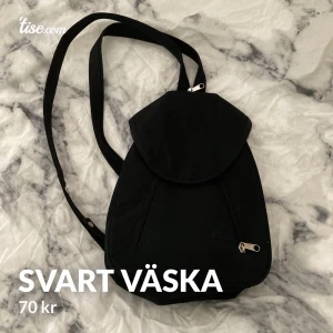 Svart väska  - Väskan har fyra fack. En på sidan, två fram på och ett fack på baksidan. Men kan sätta ihop banden med en dragkedja.