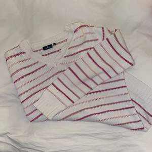 En v-ringad, vit- och rosarandig ”virkad” tröja från ISOLDE, storlek L